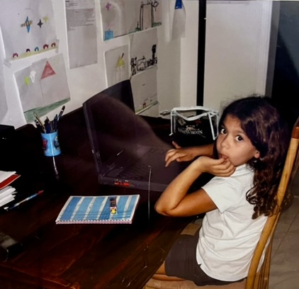 Eva enfant, assise devant un ordinateur portable.