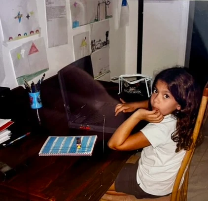 Eva enfant, assise devant un ordinateur.